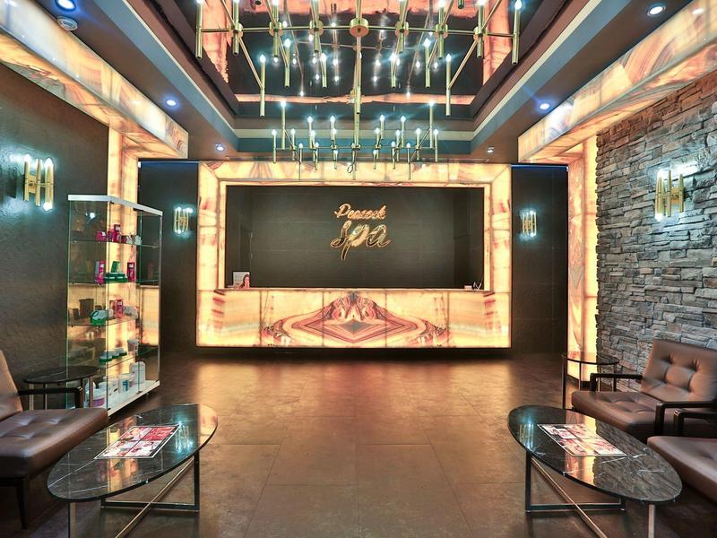 Moderna recepción de hotel con sillones de cuero, mesas de cristal y mostrador iluminado cálidamente.