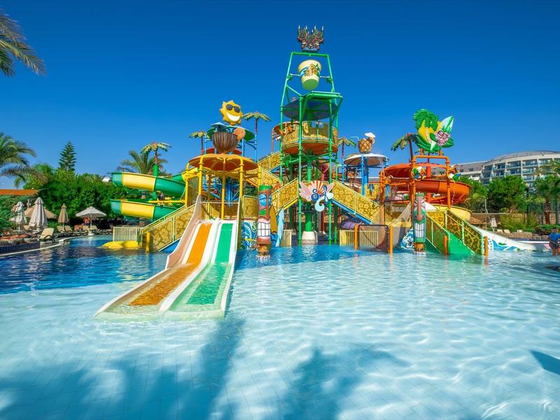 Gran parque acuático colorido con toboganes y juegos de agua bajo un cielo azul claro.