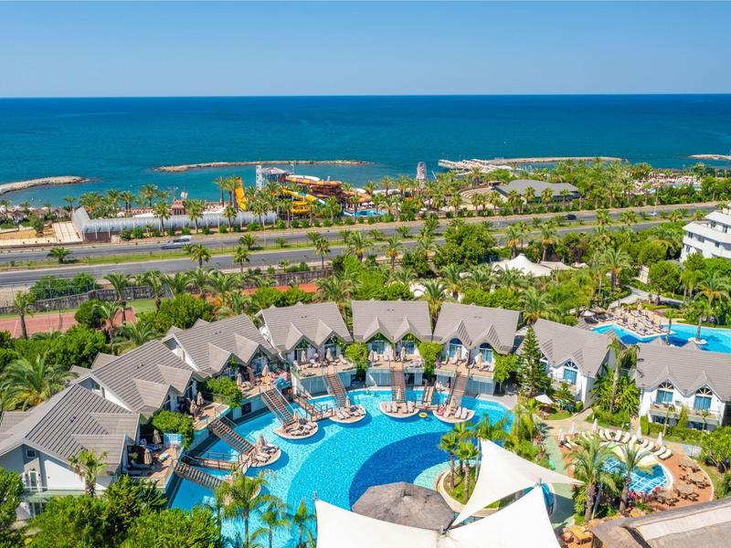 Vista aérea de un resort con una gran piscina, tumbonas y vista al mar.