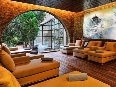 Gezellige lounge met banken, houten vloer en uitzicht op tuin door grote ramen.