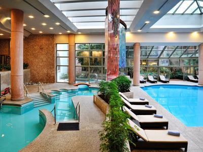 Licht binnenzwembad met ligstoelen en glazen dak in een hotel.