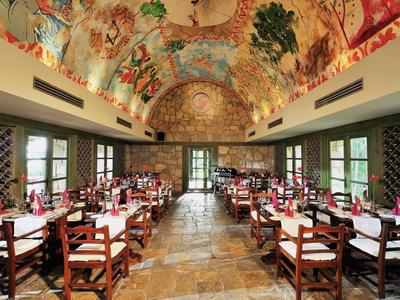 Elegant restaurant met beschilderd gewelfd plafond en houten tafels in rijen