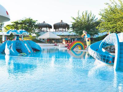 Barevné vodní hřiště s skluzavkami a bazénem na slunném venkovním prostoru.