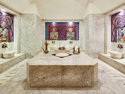 Luxe Turks bad met marmeren muren, centrale wasbak en decoratieve ramen