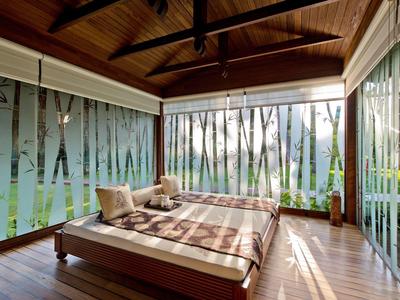 Gezellige slaapkamer met houten vloer en grote ramen met uitzicht op een bos.