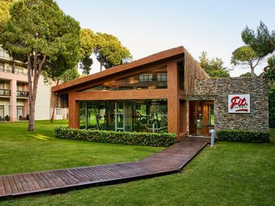 Moderní hotelová budova se šikmou střechou a dřevěnou cestou v upravené zahradě