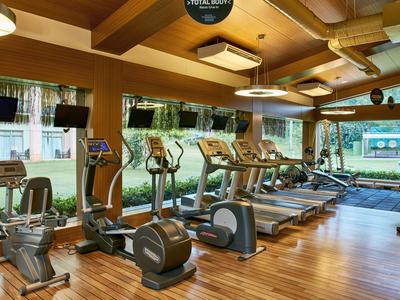 Moderní posilovna s vybavením před velkými okny a dřevěnou podlahou