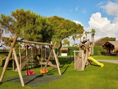Speelplaats met schommels en glijbaan op goed onderhouden gras bij blauwe lucht