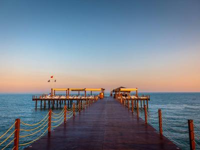 Lange steiger loopt het rustige water in onder een heldere zonsondergang