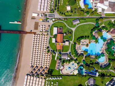 Letecký pohled na resort s bazény, lehátky a přímým přístupem na pláž.