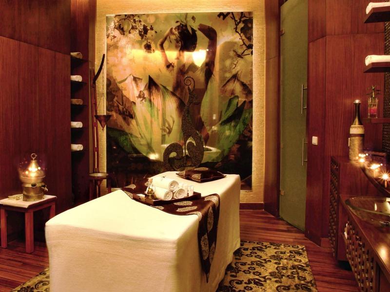 Elegant spa-ruimte met massagetafel, warme verlichting en decoratieve muurschildering.