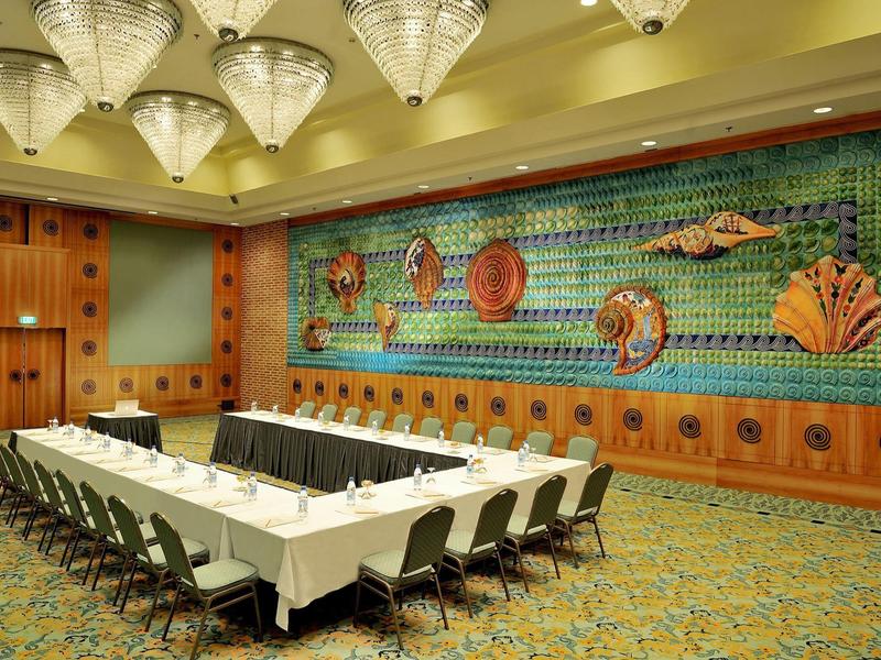 Vergaderruimte met U-vormige tafel, witte stoelen en kleurrijke zee-muurdecoratie