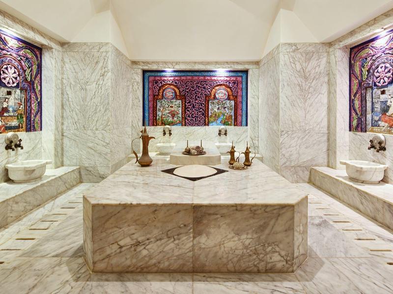 Luxe Turks bad met marmeren muren, centrale wasbak en decoratieve ramen