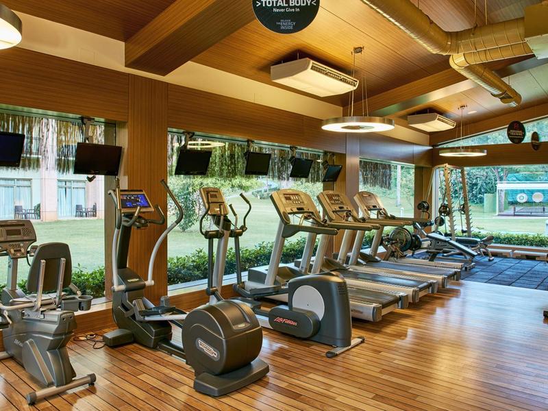 Moderne fitnessruimte met cardioapparatuur en houten vloer in een hotel.