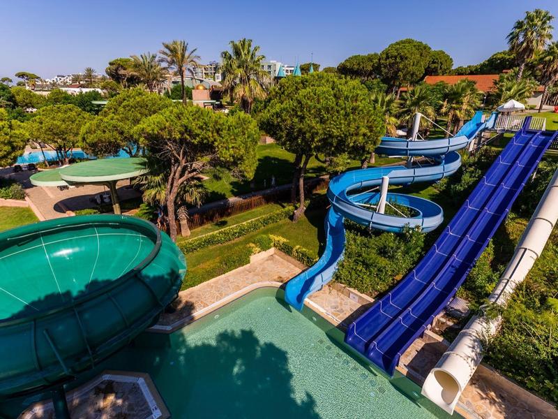 Waterpark met drie glijbanen omgeven door weelderig groen.