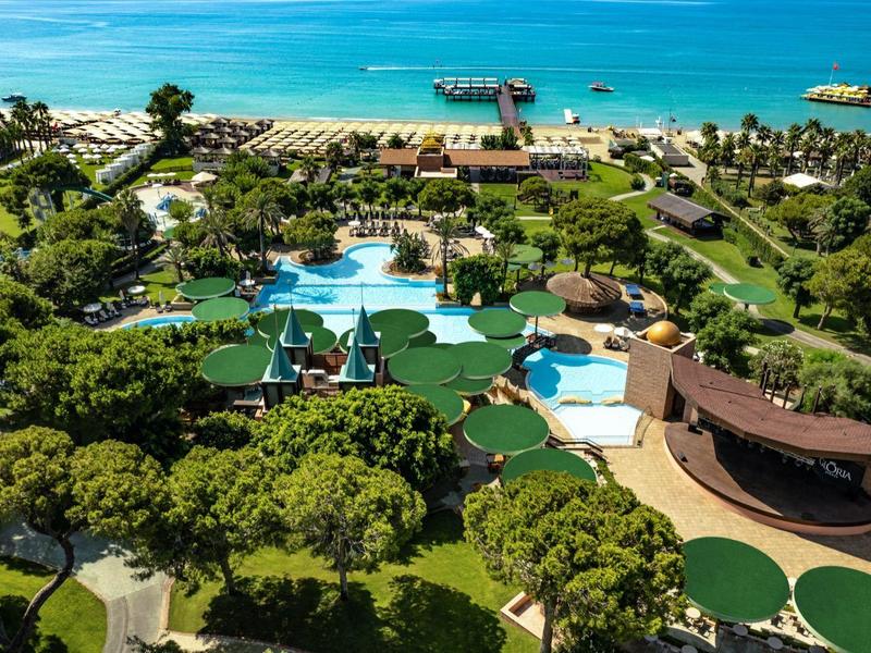 Luchtfoto van een strandresort met zwembaden, groene gebieden en directe toegang tot zee.