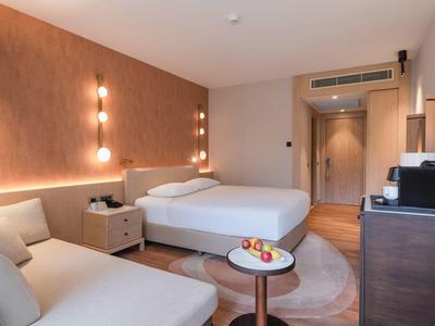 Modernes Hotelzimmer mit Doppelbett, Sitzbereich, Nachttisch und Fernseher.