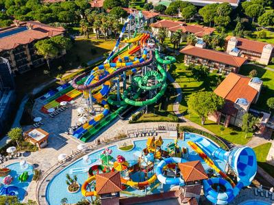 Bunte Wasserparklandschaft in einem Resort mit Rutschen, Pools und umgeben von grünen Bäumen.