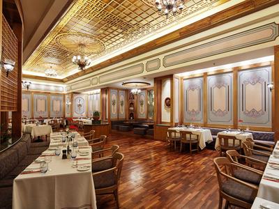 Eleganter Speiseraum mit Holzboden, Tischen mit weißen Tüchern und verzierten Wänden in einem Hotel.