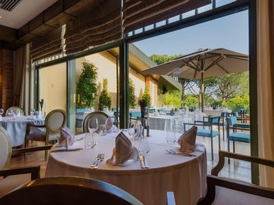 Elegantes Restaurant mit Tisch, Stühlen und Blick auf eine Terrasse mit Sonnenschirmen.