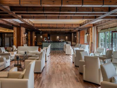 Helle Hotel-Lounge mit bequemen weißen Sesseln, Holzboden und großem Fenster für natürlichen Lichteinfall.