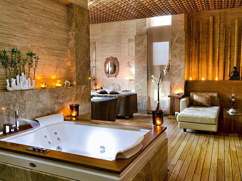 Luksusowy pokój spa z jacuzzi, przytulnym miejscem do siedzenia i ciepłym drewnianym wystrojem.