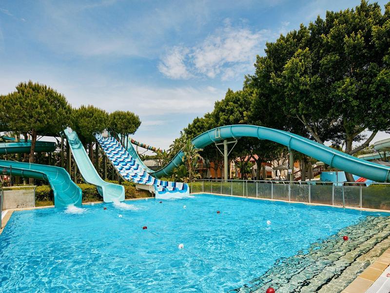 Park wodny z niebieskimi zjeżdżalniami i czystym basenem w słonecznym otoczeniu