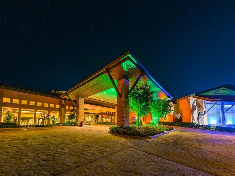 Nowoczesny budynek hotelowy nocą z kolorowym oświetleniem i czystym, gwiaździstym niebem.