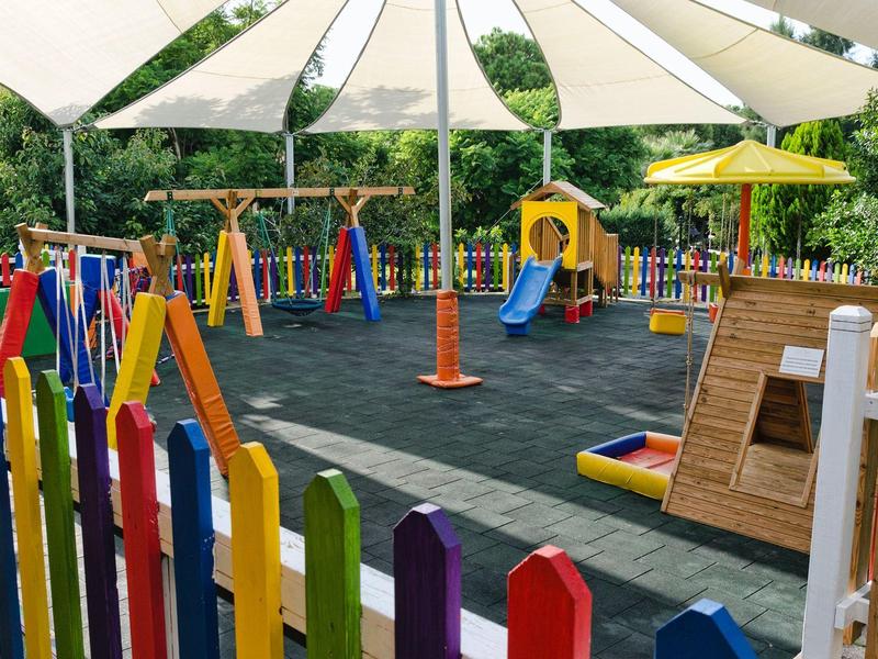 Kolorowy plac zabaw dla dzieci z sprzętem i osłoną przeciwsłoneczną na zewnątrz.