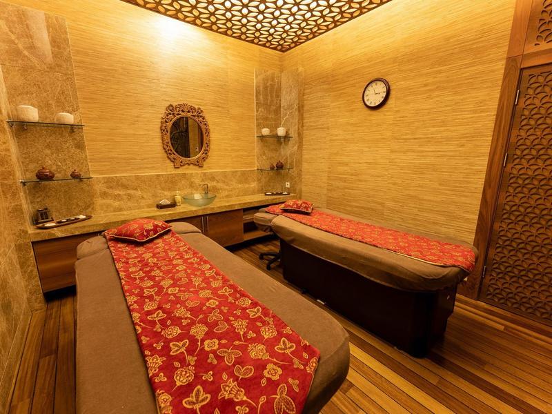 Przytulny pokój wellness z dwoma stołami do masażu i ciepłym drewnianym wystrojem.