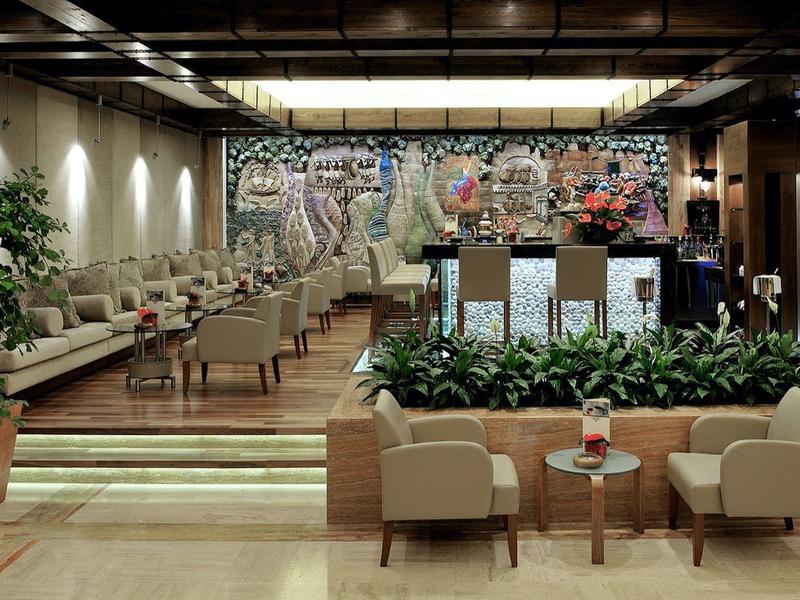Nowoczesne lobby hotelowe z miejscami do siedzenia, roślinami i kolorową malowidłem na ścianie.