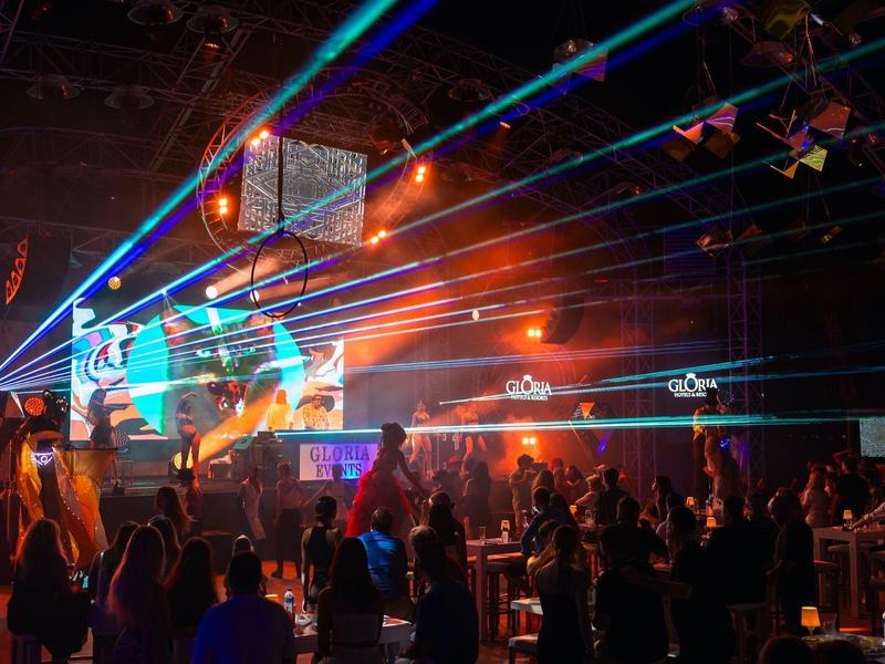 Żywa przestrzeń wewnętrzna z tłumem cieszącym się pokazem świateł i laserów.