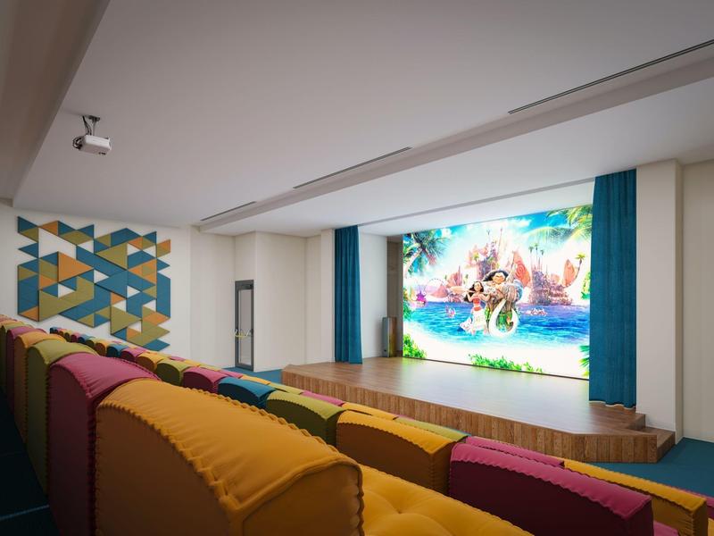 Nowoczesna sala kinowa z kolorowymi rzędami siedzeń i dużym ekranem z filmem animowanym.