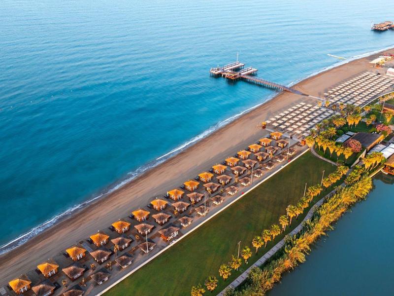 Zdjęcie z powietrza długiej plaży z parasolami i molo na czystym, błękitnym morzu.