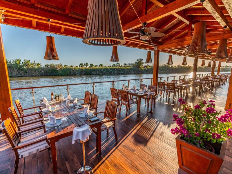 Otwarta restauracja z drewnianym sufitem z widokiem na rzekę o zachodzie słońca