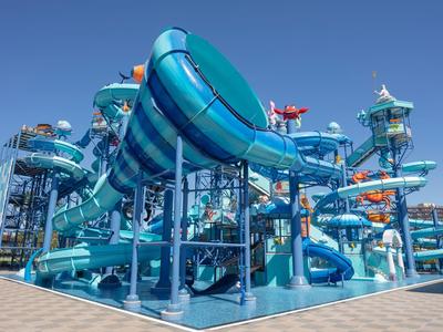 Grand parc de toboggans aquatiques extérieurs avec des toboggans bleus et turquoise sous un ciel bleu clair