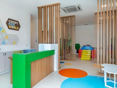 Salle de jeux lumineuse avec tapis coloré, sièges et mobilier moderne.