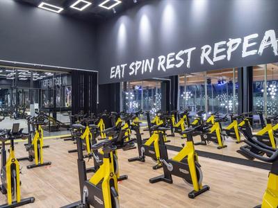 Salle de sport moderne avec plusieurs vélos de spinning jaunes et texte motivant au mur.