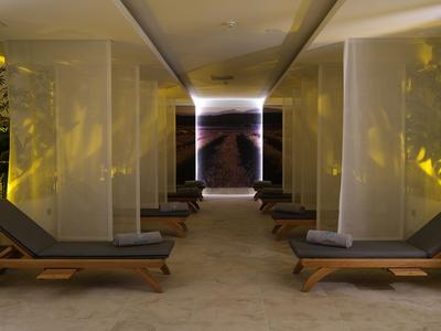 Relaxation area with lounge chairs and sheer curtains in a warmly lit room.