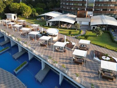 Large terrace with white furniture and umbrellas beside a blue pool at a hotel resort.