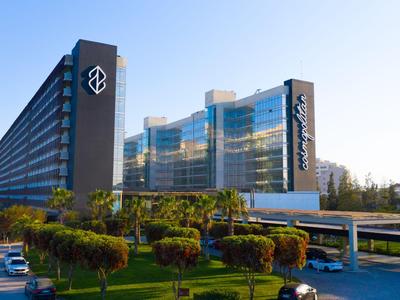 Modern hotel with glass facade and adjacent green garden under clear sky.