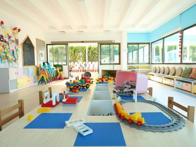 Bright hotel playroom for children with train track and chairs.