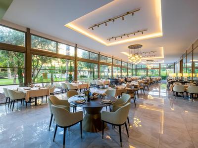 Elegant restaurant with large windows, modern furniture, and garden views.