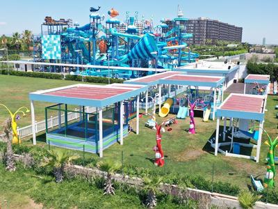 Water park with colorful water slides and covered seating areas in a green setting.