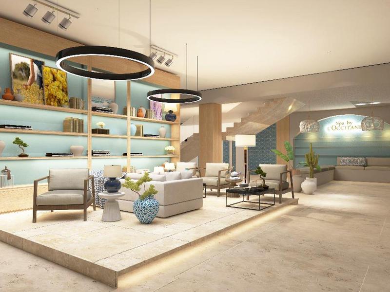 Lounge d'hôtel moderne et lumineuse avec fauteuils, canapé et étagères éclairées.