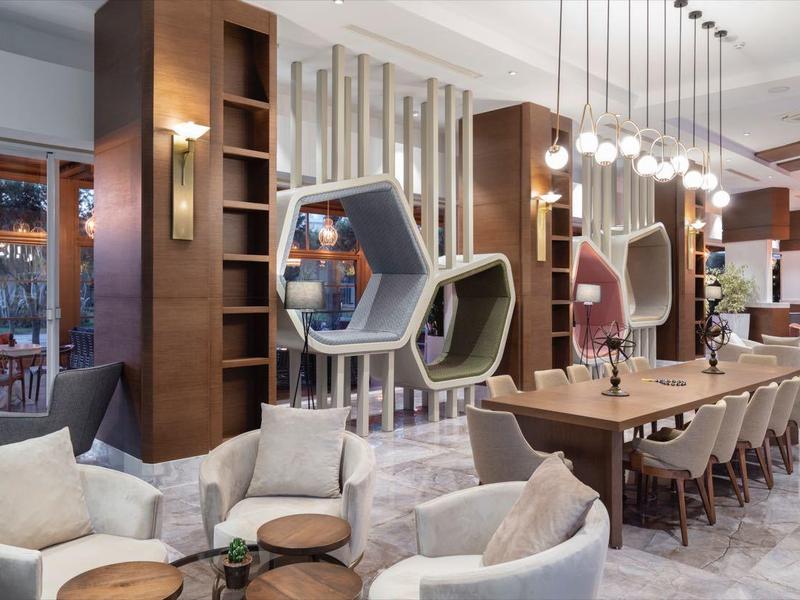 Espace lounge d'hôtel moderne avec fauteuils confortables et panneaux en bois élégants.