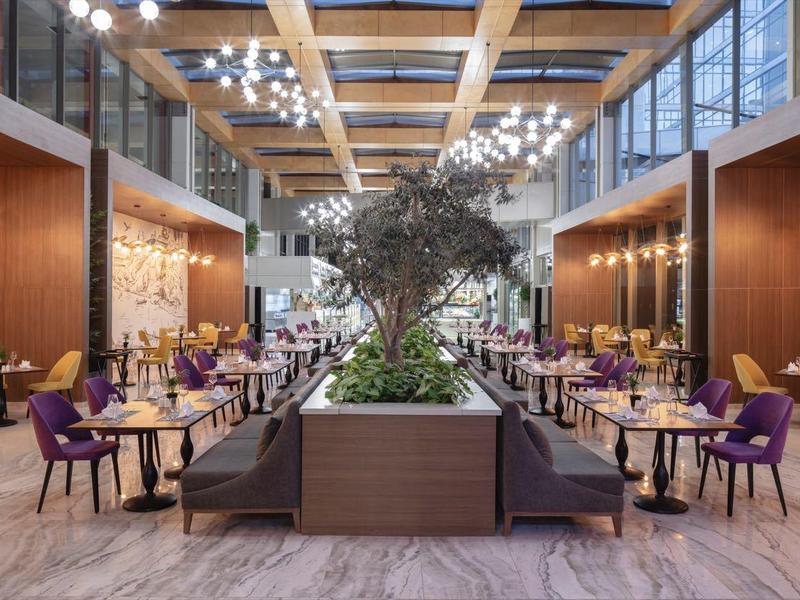 Grande salle à manger élégante avec arrangement de plantes centrales et chaises modernes.