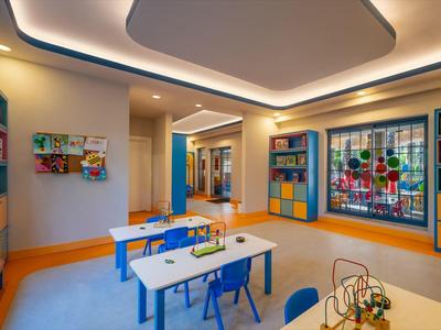 Heldere kinder speelkamer met tafels, stoelen, kleurrijke wandkasten en kunst aan muren.