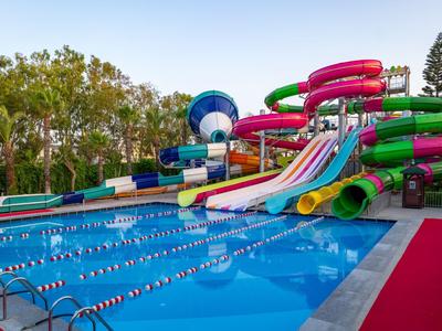 Complesso di scivoli d'acqua colorati accanto a una piscina in una località turistica di giorno.