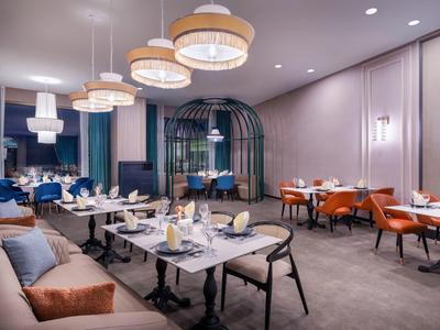 Modern hotelrestaurant met stijlvolle verlichting en tafelopstelling in warme kleuren.